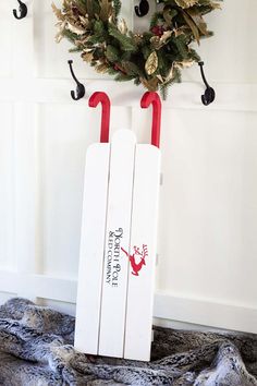 a christmas wreath hanging on the side of a door with two red handled shovels