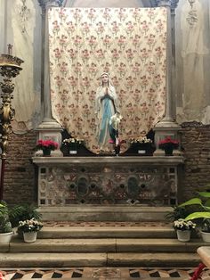 the statue of jesus is on display in this ornate room with floral curtains and potted plants