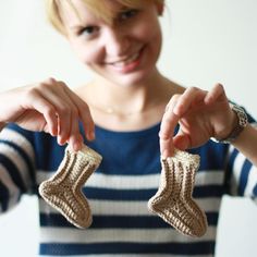 a woman holding two knitted socks in her hands