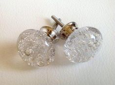 two clear glass knobs on a white surface