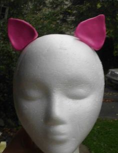 a white mannequin head with pink ears on it