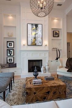 a living room filled with furniture and a fire place under a chandelier hanging from the ceiling