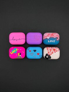 four different colored rocks with hearts and love written on the top one is pink, blue, green, purple, and yellow