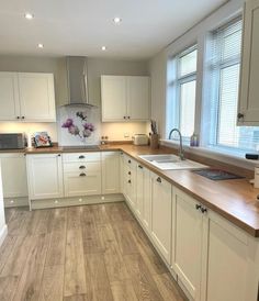 an empty kitchen with white cabinets and wood flooring on the counter top, along with a sink