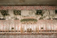 an elaborately decorated table with flowers and greenery on the wall, along with candles