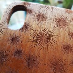 a wooden cutting board with an intricate design on it's side and a hole in the middle