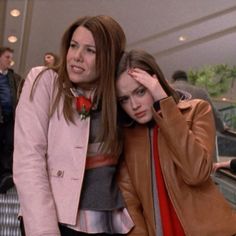 two women standing next to each other in front of an escalator with their hands on their head