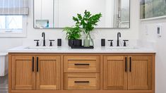 a bathroom with two sinks, mirrors and plants in the middle of the sink area