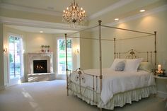 a bedroom with a bed, chandelier and fireplace in the middle of it