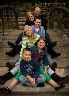 a family sitting on steps in front of some stairs with their arms around each other