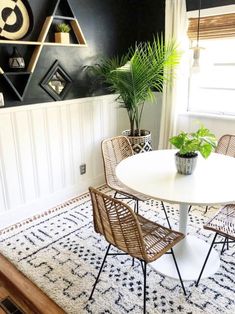 a dining room table with chairs and a potted plant on the wall behind it