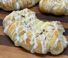 several pastries with white icing sitting on top of a wooden cutting board next to each other