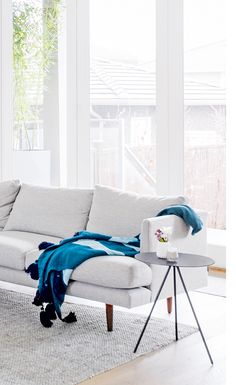 a living room with a white couch and blue throw blanket on the back of it