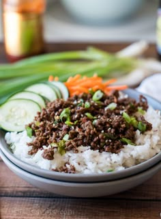 a bowl filled with rice, meat and veggies on top of a wooden table