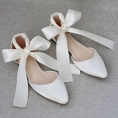 three pairs of white shoes with bows on them