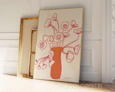 an orange vase filled with flowers sitting on top of a wooden floor next to a white wall