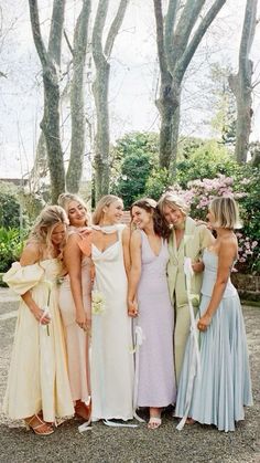 a group of women standing next to each other wearing dresses and holding bouquets in their hands