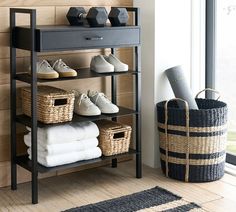 a shelf with baskets and shoes on it next to a window in a living room