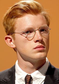 a young man wearing glasses and a suit