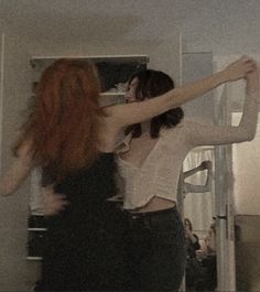 two young women are dancing together in the room