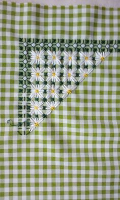 a green and white checkered table cloth with daisies on the side, stitched together