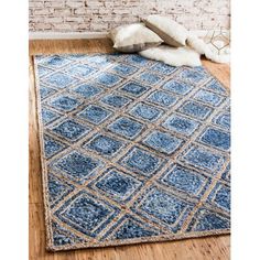 a blue area rug on the floor in front of a brick wall and wooden floors