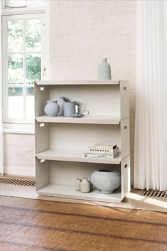 a white shelf with vases and books on it