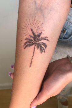 a woman's arm with a palm tree tattoo on it