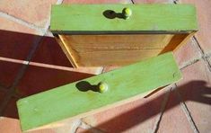 two wooden boxes sitting on top of a red brick floor with green handles and knobs