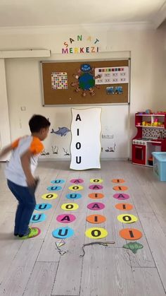 a young boy is playing with letters on the floor in front of a bulletin board