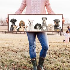 a woman holding up a framed photo with dogs on it