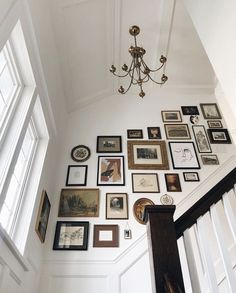 a staircase with many framed pictures on the wall and a chandelier hanging from the ceiling