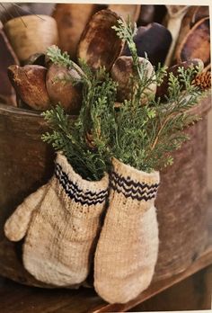 a pair of mittens sitting on top of a wooden table next to bread and vegetables