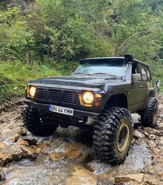 a jeep driving through some rocks in the water