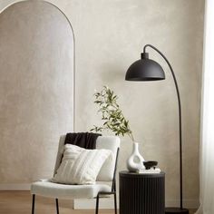 a white chair sitting next to a tall black lamp