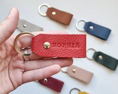 a person holding a red leather keychain in front of several different colored keys