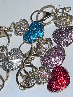 several heart shaped key chains are shown on a white surface with red, blue, and pink glitters