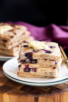 stack of pancakes with butter and blueberry toppings on white plate next to fork