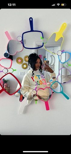 a woman sitting on top of a white wall with lots of colorful objects around her