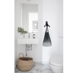 a white bathroom with a basket on the floor