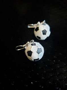 two soccer balls are sitting on top of each other, with silver earwires