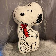 a stuffed snoopy holding a red bow