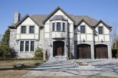 a large white and brown house with two garage doors on the front door is shown