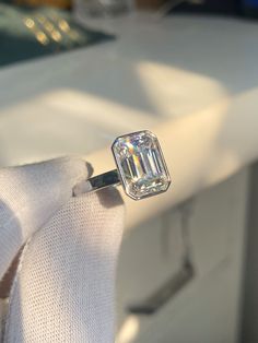 a diamond ring sitting on top of a white cloth in front of a window sill