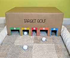 a cardboard box sitting on top of a carpeted floor next to balls and tees