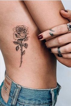 a woman's lower body with tattoos and roses on her thighs, holding onto the side of her stomach