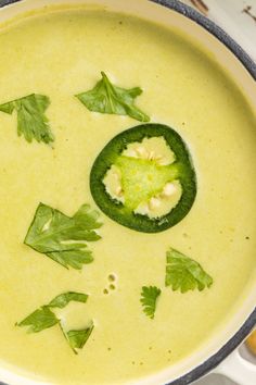 a pot filled with broccoli soup and topped with parsley on the side