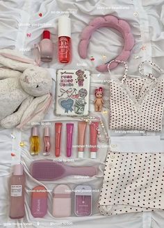 the contents of a purse laid out on a white sheet with pink accessories and nail polish