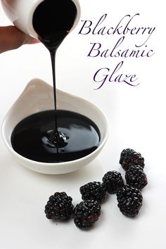 blackberry balsamic glaze is being poured into a white bowl with blackberries