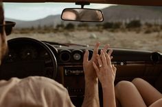 a man and woman sitting in the back seat of a car with their hands up